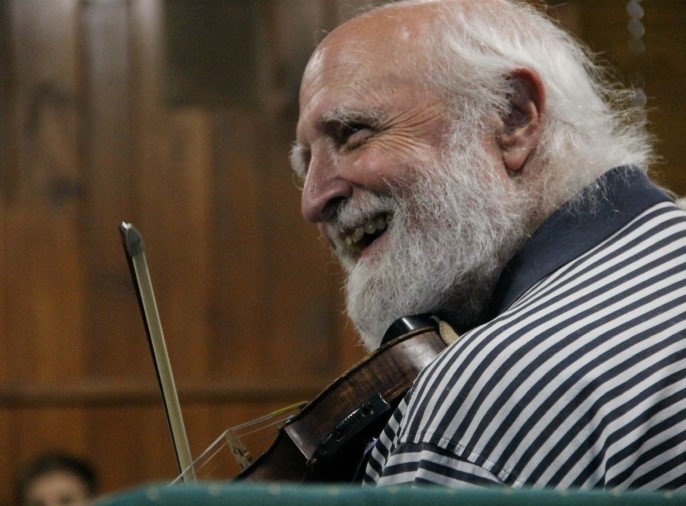 photo of a man grinning while playing the fiddle